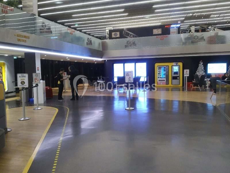 Espace intérieur moderne avec sol brillant, distributeurs automatiques, sièges et éclairage au plafond.