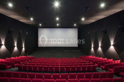 Bâtiment moderne avec façade blanche, toit en surplomb et grandes baies vitrées, entouré de végétation.