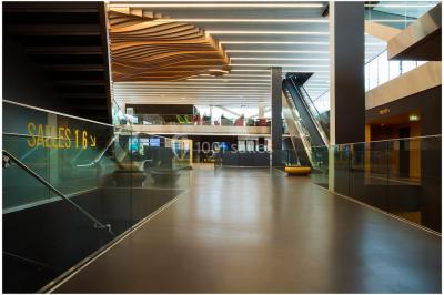 Bâtiment moderne avec façade blanche, toit en surplomb et grandes baies vitrées, entouré de végétation.