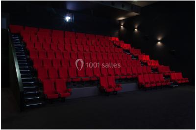 Bâtiment moderne avec façade blanche, toit en surplomb et grandes baies vitrées, entouré de végétation.