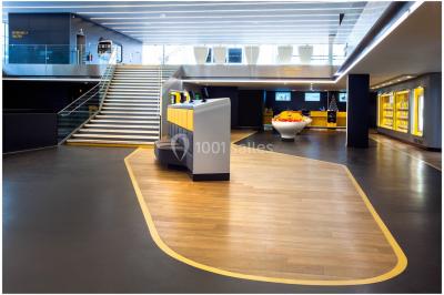 Bâtiment moderne avec façade blanche, toit en surplomb et grandes baies vitrées, entouré de végétation.