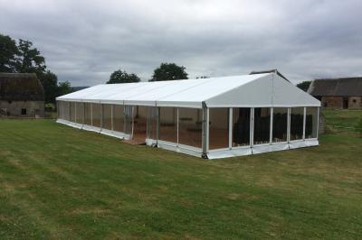 Salon avec plafond en poutres apparentes, mobilier ancien, canapé, fauteuils et éclairage chaleureux.