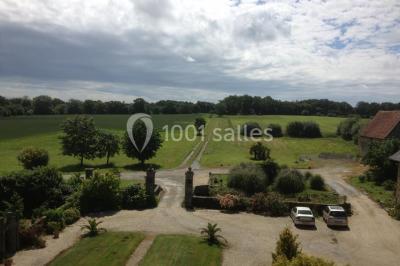 Salon avec plafond en poutres apparentes, mobilier ancien, canapé, fauteuils et éclairage chaleureux.