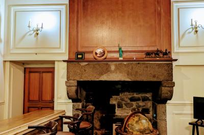 Salon avec plafond en poutres apparentes, mobilier ancien, canapé, fauteuils et éclairage chaleureux.