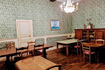 Salon avec plafond en poutres apparentes, mobilier ancien, canapé, fauteuils et éclairage chaleureux.