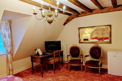 Salon avec plafond en poutres apparentes, mobilier ancien, canapé, fauteuils et éclairage chaleureux.