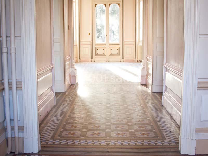 Vue d'un couloir lumineux avec un sol en carreaux décoratifs et des portes vitrées donnant sur l'extérieur.