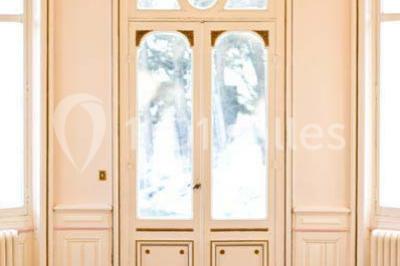 Grande maison en pierre blanche entourée d'arbres, avec une allée et un jardin ensoleillé à l'avant.