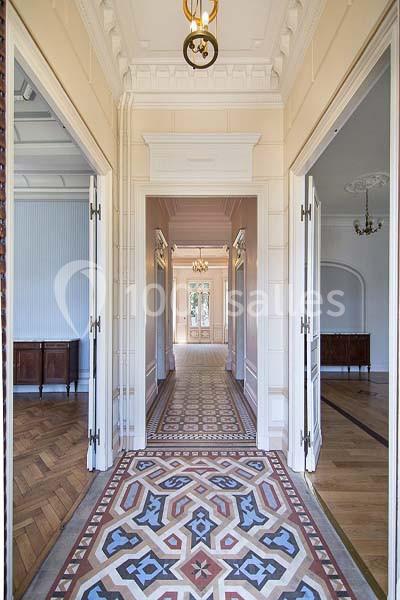 Vue d'un couloir lumineux avec carrelage géométrique, moulures au plafond et portes ouvertes sur des pièces adjacentes.