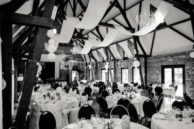 Table élégamment dressée avec menu, couverts, verres et une fleur rouge en centre de table, éclairée par la lumière…