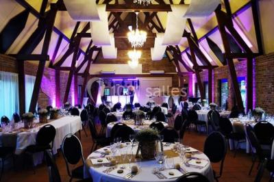 Table élégamment dressée avec menu, couverts, verres et une fleur rouge en centre de table, éclairée par la lumière…