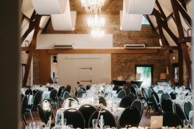 Table élégamment dressée avec menu, couverts, verres et une fleur rouge en centre de table, éclairée par la lumière…