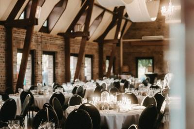 Table élégamment dressée avec menu, couverts, verres et une fleur rouge en centre de table, éclairée par la lumière…