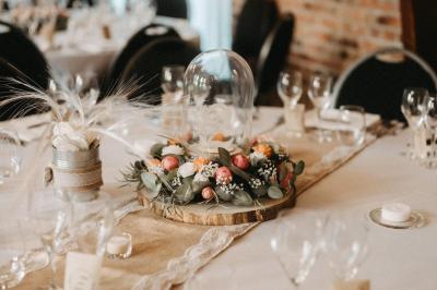 Table élégamment dressée avec menu, couverts, verres et une fleur rouge en centre de table, éclairée par la lumière…