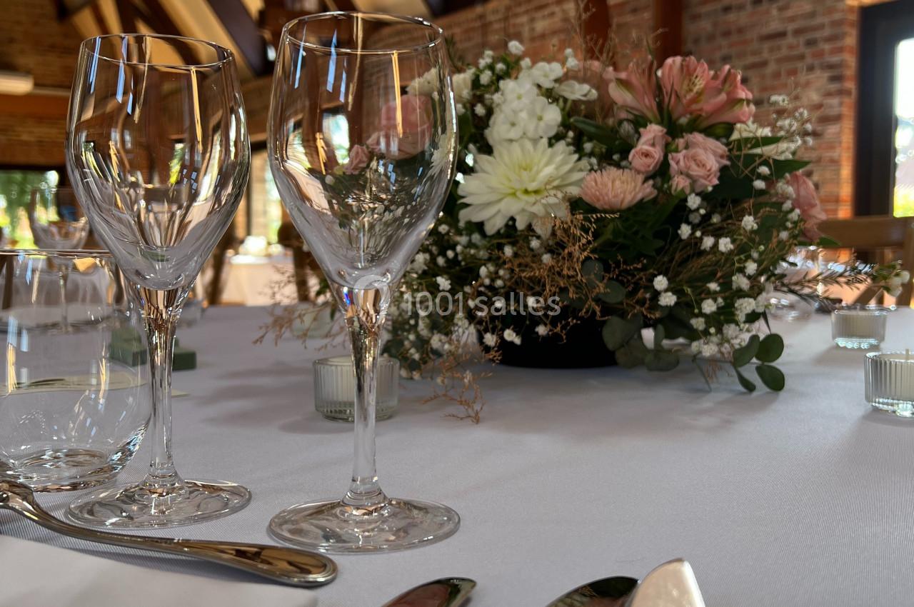 Table élégamment dressée avec des verres à vin, des couverts brillants et un centre de table floral dans une salle en…