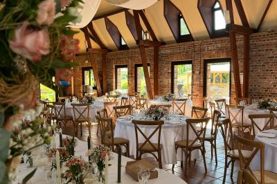 Table élégamment dressée avec menu, couverts, verres et une fleur rouge en centre de table, éclairée par la lumière…