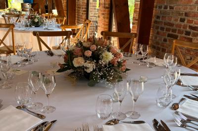 Table élégamment dressée avec menu, couverts, verres et une fleur rouge en centre de table, éclairée par la lumière…
