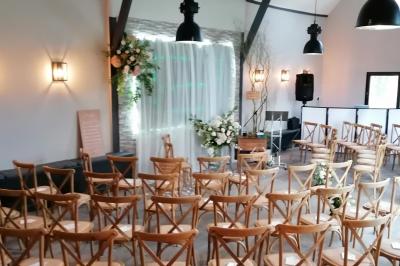 Table élégamment dressée avec menu, couverts, verres et une fleur rouge en centre de table, éclairée par la lumière…