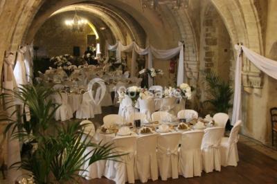 Château en pierre éclairé par des lampadaires au crépuscule, entouré d'arbres et d'une allée gravillonnée.
