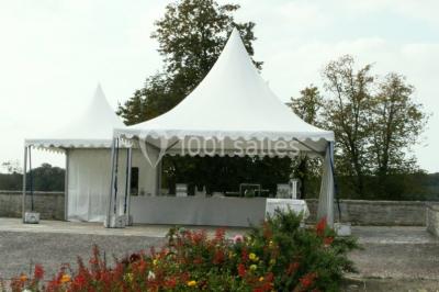 Château en pierre éclairé par des lampadaires au crépuscule, entouré d'arbres et d'une allée gravillonnée.