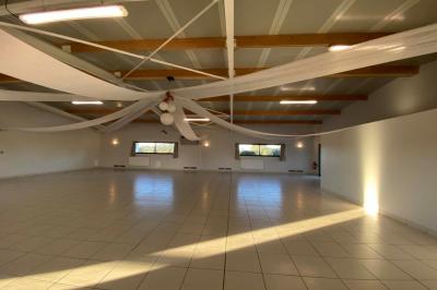 Salle lumineuse avec plafond en bois, grandes baies vitrées, carrelage au sol et chariots de rangement sur roulettes.