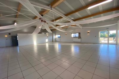 Salle lumineuse avec plafond en bois, grandes baies vitrées, carrelage au sol et chariots de rangement sur roulettes.