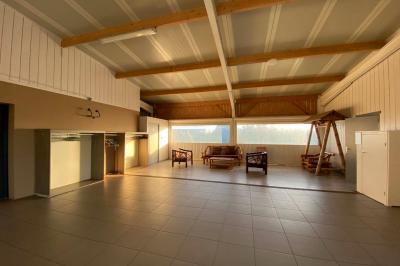 Salle lumineuse avec plafond en bois, grandes baies vitrées, carrelage au sol et chariots de rangement sur roulettes.