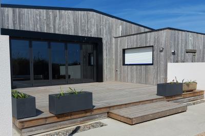 Salle lumineuse avec plafond en bois, grandes baies vitrées, carrelage au sol et chariots de rangement sur roulettes.