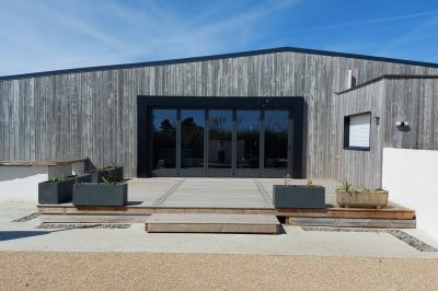 Salle lumineuse avec plafond en bois, grandes baies vitrées, carrelage au sol et chariots de rangement sur roulettes.