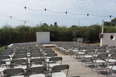 Salle lumineuse avec plafond en bois, grandes baies vitrées, carrelage au sol et chariots de rangement sur roulettes.