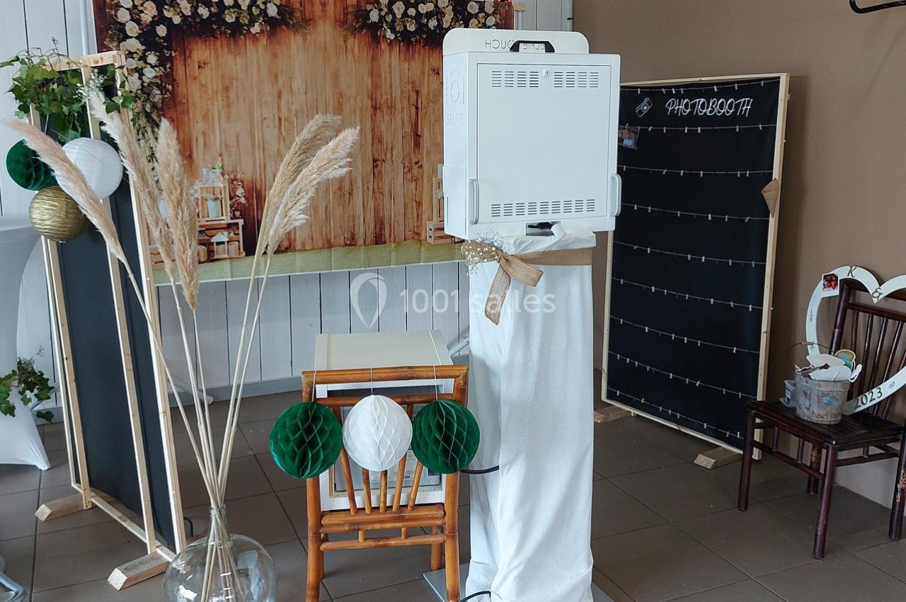 Photobooth installé dans un espace décoré avec des éléments naturels, un fond en bois et des accessoires festifs.
