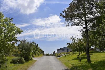 Salle lumineuse avec plafond en bois, grandes baies vitrées, carrelage au sol et chariots de rangement sur roulettes.