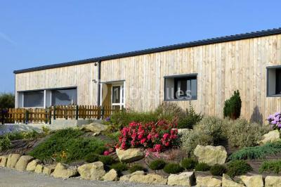 Salle lumineuse avec plafond en bois, grandes baies vitrées, carrelage au sol et chariots de rangement sur roulettes.