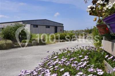 Salle lumineuse avec plafond en bois, grandes baies vitrées, carrelage au sol et chariots de rangement sur roulettes.