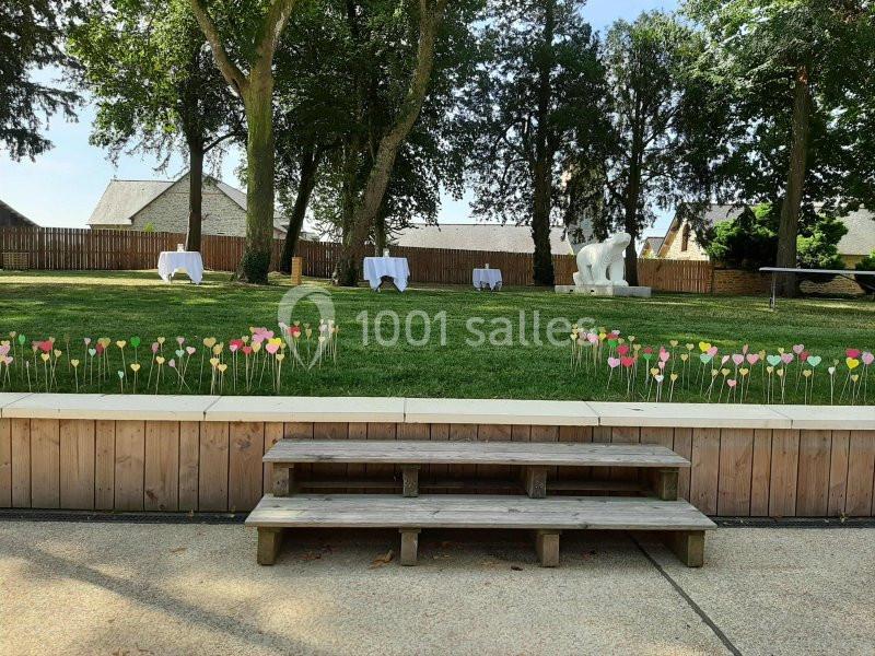 Pelouse avec des tables blanches en arrière-plan, décorée de cœurs colorés sur des tiges en premier plan.