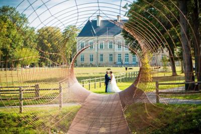 Miniature Location salle Piré-sur-Seiche (Ille-et-Vilaine) - Domaine du Château des Pères #5 Lit double avec une couverture blanche, des coussins colorés et une robe de mariée posée sur le côté.