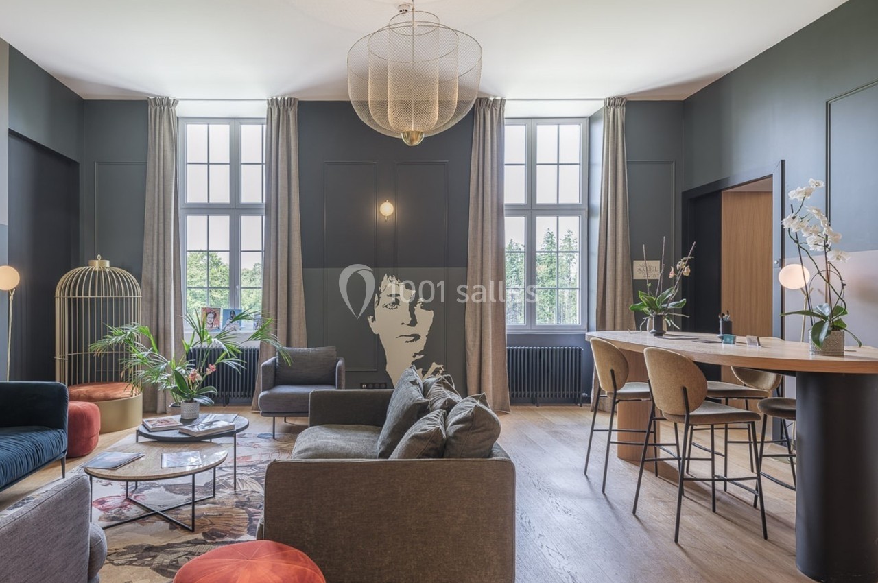 Salon moderne avec canapés, table basse, bar, grandes fenêtres et décoration élégante dans des tons sombres.