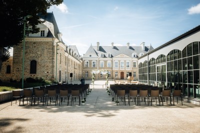 Deux mains se tenant devant un bâtiment moderne aux formes arrondies et à la façade beige.