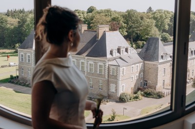 Deux mains se tenant devant un bâtiment moderne aux formes arrondies et à la façade beige.