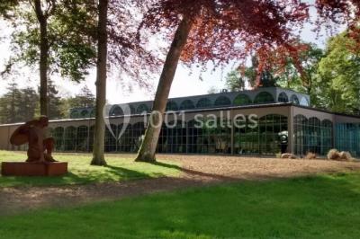 Salle de restaurant chaleureuse avec tables en bois, chaises en rotin, rideaux rouges et éclairage suspendu.