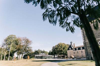 Salle de restaurant chaleureuse avec tables en bois, chaises en rotin, rideaux rouges et éclairage suspendu.