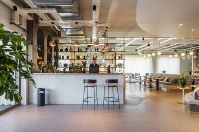 Salle de restaurant chaleureuse avec tables en bois, chaises en rotin, rideaux rouges et éclairage suspendu.