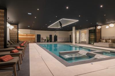 Salle de restaurant chaleureuse avec tables en bois, chaises en rotin, rideaux rouges et éclairage suspendu.