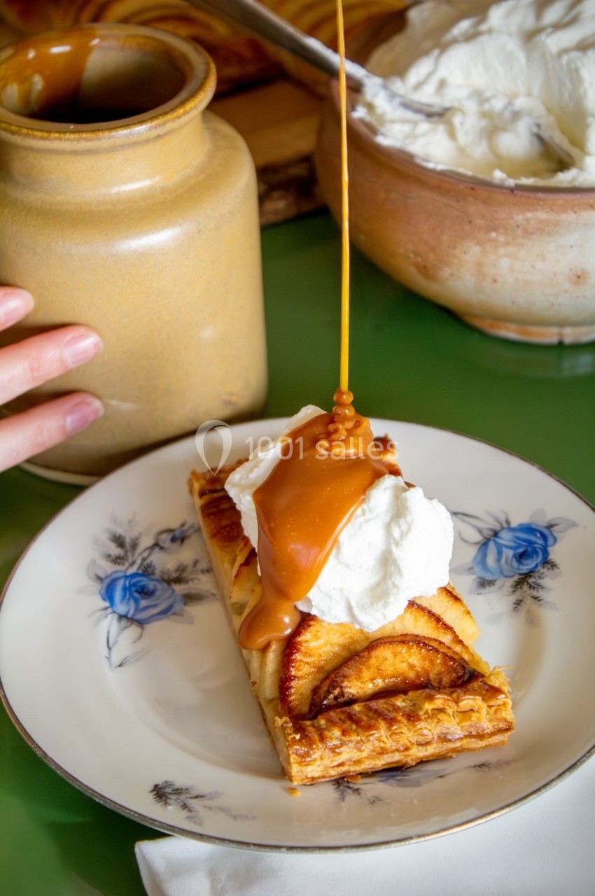 Tarte aux pommes servie avec une cuillère de crème fouettée, nappée de caramel liquide.