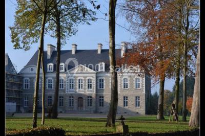 Salle de restaurant chaleureuse avec tables en bois, chaises en rotin, rideaux rouges et éclairage suspendu.