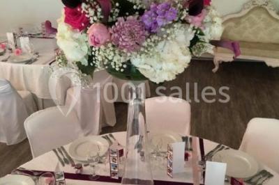 Décor champêtre avec fauteuils, tapis, grande horloge et lanternes sous un arbre, ambiance vintage en extérieur.