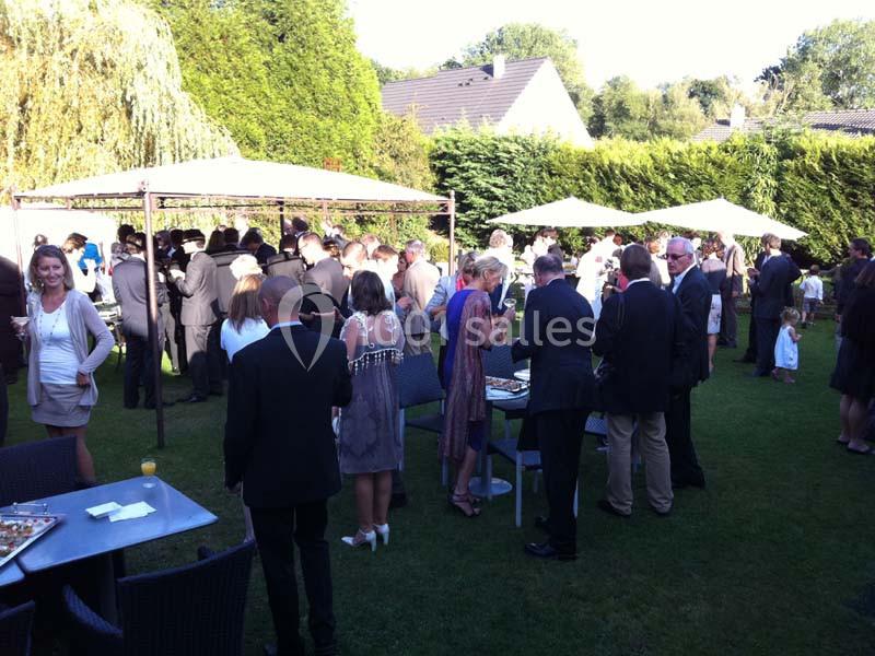 Groupe de personnes en tenue habillée réunies dans un jardin pour un événement en plein air.