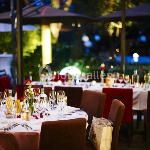 Salle de restaurant élégante en soirée, avec tables dressées, nappes blanches, bougies et éclairage tamisé.