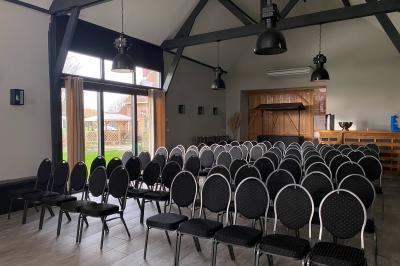 Tente blanche installée sur une pelouse, accueillant un événement avec des invités debout autour de tables hautes.