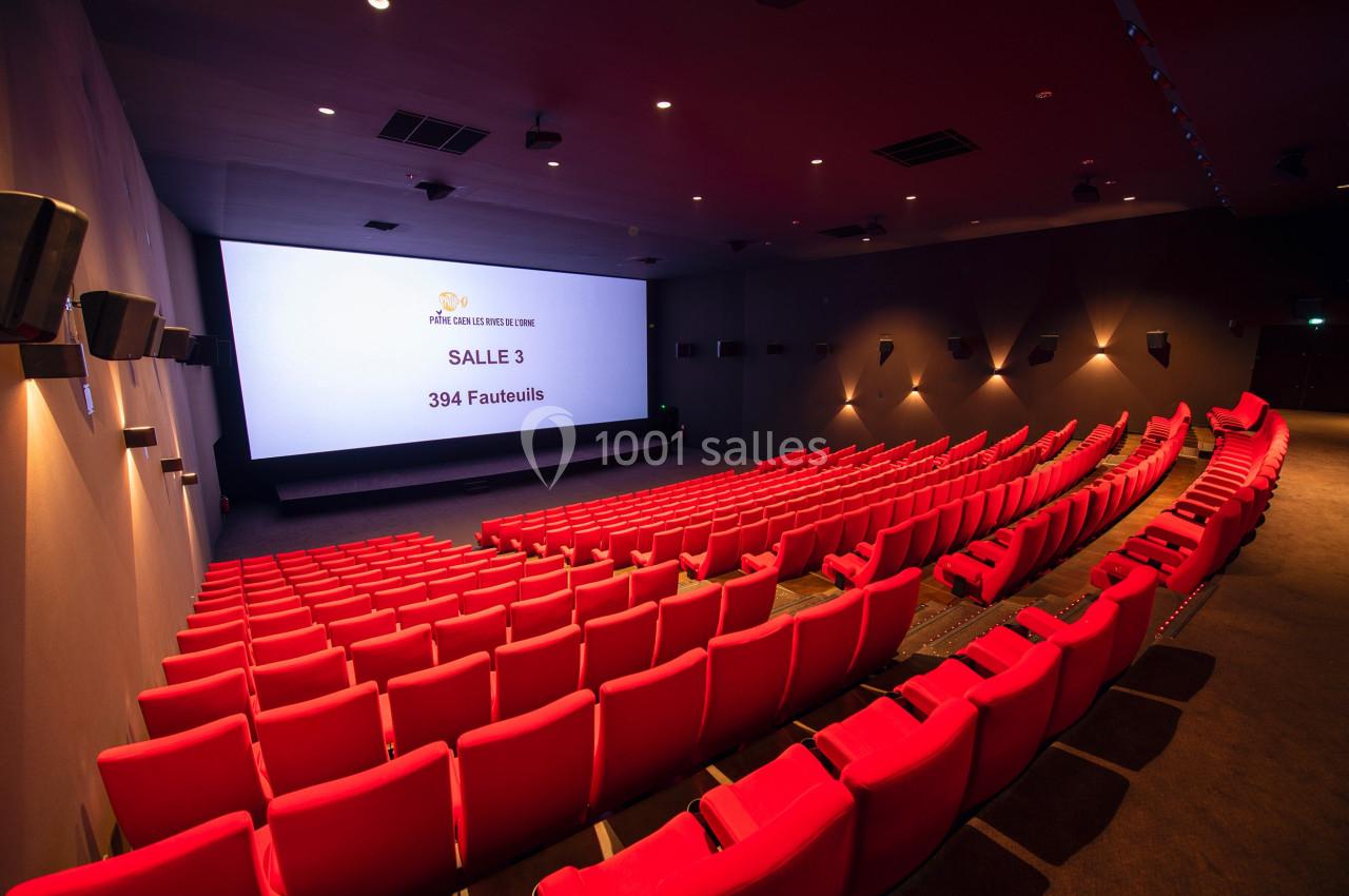 Salle de cinéma vide avec des rangées de fauteuils rouges et un écran affichant ’Salle 3, 394 fauteuils’.